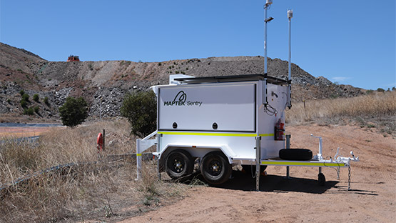 A Maptek Sentry Trailer set up by the wall of a tailings dam.