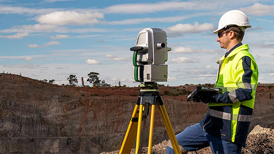 A Maptek XR3 laser scanner being operated by someone with a tablet on a mine site.
